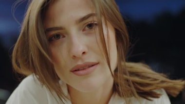 Şehir ışıkları altında doğal güzelliğini sergileyen dingin bir genç kadının detaylı portresi. Şehir sakinliğinin ve düşünceli ifadenin bir anını yakalıyor..