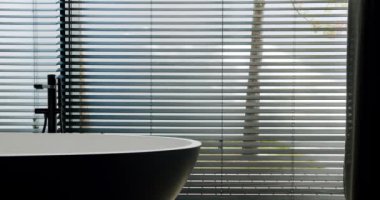 Modern bir banyo manzarası. Çağdaş jaluziler vasıtasıyla çarpıcı bir doğa manzarası olan büyük bir küvet. Dış Görünümü Perdeler Arasında olan Modern Banyo İçi