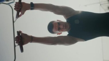 Yoğun Direniş Grubu Antrenmanına Odaklanan Genç Adam. Genç bir atletik, bir direniş grubuyla antrenman yapıyor. Bir spor salonunda gücünü ve kararlılığını gösteriyor. Dikey video.