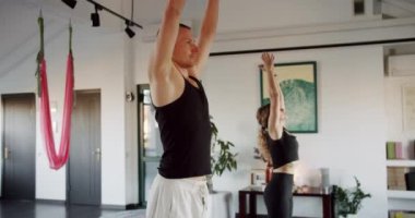 Erkek ve kadın birlikte yoga yapıyorlar. Çıplak ayaklı kadın ve erkeğin hafif stüdyodaki yoga seansı sırasında aşağı ve yukarı bakan köpek pozları çekimleri..