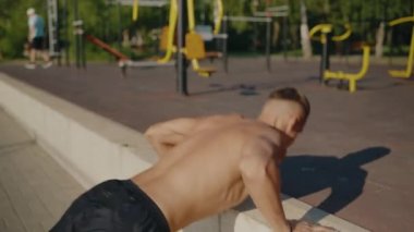 Parktaki açık hava spor salonunda egzersiz yapan üstsüz bir adam. Doğal ortamda vücut geliştirme ve güç eğitimine odaklanıyor. Spor Salonu Spor Salonu 'nda Erkek Egzersizi