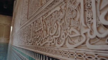Detaylı oymalar ve zarif kaligrafi ile bir duvarda sergilenen karmaşık Fas sanatı. Geleneksel tasarım zengin kültür mirasını yansıtıyor. Sıcak renkler ve süslü İslami desenler