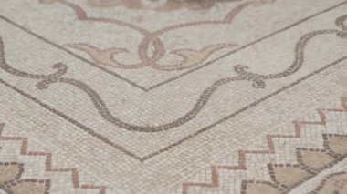 Volubilis, Fas 'taki karmaşık mozaik zeminin yakın görüntüsü. Detaylı fayanslar, sanatsal desenleri toprak tonlarında sergiliyor. Bu antik Roma şehri tarihe bir göz atıyor.