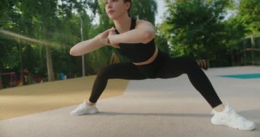 Egzersiz yapan, eğilip dışarı uzanan çekici genç bir kadın. Sportif kız jimnastik yapıyor. Sağlıklı bayan sporcu açık hava sporları antrenmanından zevk alır..