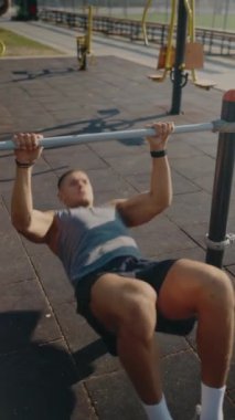 Genç bir adam, açık hava spor salonunda barfiks çekerek yoğun bir egzersiz yapıyor. Doğal gün ışığında güç ve zindelik gelişimine odaklanmış. Atletik Adam Spor Salonunda Egzersiz Yapıyor