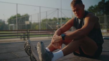 Genç erkek sporcu açık hava basketbol sahasında, güneşin tadını çıkarıyor. Egzersiz rutinini yansıtarak zorlu bir çalışmadan sonra azim ve rahatlık yayıyor..