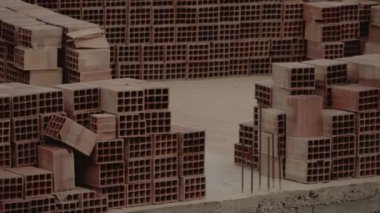 Terracotta tuğlaları bir Fas şantiyesinde kullanılmaya hazırdır. Metal demir çubuklar kumlu zeminden dışarı fırlıyor. Sahne çalışkanlığı ve inşaatı simgeliyor..