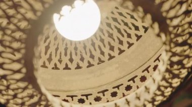 Süslü bir Fas lambasına yakın çekim. Işık, karmaşık desenleri ve tasarımları aydınlatarak sıcak ve davetkar bir ortam yaratıyor. Bu geleneksel lamba biraz Fas kültürü katıyor. Süsleme Lambası