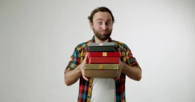 Bir adam bir sürü renkli hediye kutusu tutuyor ve komik surat yapıyor. Tatiller, kutlamalar, hediyeler ve neşeli duygularla ilgili projeler için mükemmel. Heyecan, mizah ya da beklenti..
