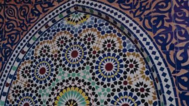Geleneksel Fas fayans mozaiğinin yakın görüntüsü. Karmaşık geometrik ve çiçek desenli. Canlı renkler ve el yapımı detaylar Fas sanatının görsel olarak zengin bir görüntüsünü oluşturuyor.