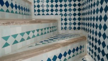 Karmaşık Fas fayanslarının bir merdiveni dekore etmesi. Kamera renkli geometrik desenleri tarıyor, işçiliği ve kültürel estetiği vurguluyor..