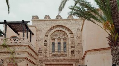 Geleneksel Fas mimarisi. Karmaşık detaylar ve sıcak toprak tonlarıyla. Bu bina eşsiz bir kemer ve dekoratif desenlere sahiptir. Bir palmiye ağacı egzotik ambiyansı artırır. seyahat