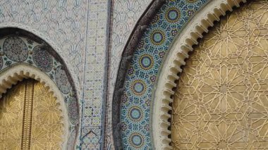 Fes, Fas 'taki Kraliyet Sarayı' nın süslü altın kapıları ve renkli mozaik fayansları. Bu detaylı bakış açısı, Fas mimarisinin karmaşık sanat ve işçiliğini gözler önüne seriyor..