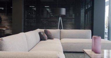 Modern gray beige sofa . Modern and Cosy House. Luxury Apartment. Modern Furniture in cozy Penthouse. Modern Living Room Interior With Comfortable Sofa and black minimalist floor lamp and black blinds