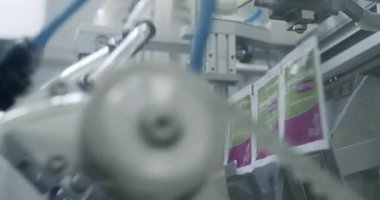 Robot kol, ilaç paketini taşıma bandına koydu. Otomatik üretim hattında paketlenmiş mallar. Uyuşturucu ambalajı. İlaç paketleme makinesi..