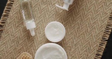 Cilt bakımı için doğal kozmetik ürünleri. Kremalı parlak kozmetik kavanozu. Farklı kozmetik şişelerden oluşan bir grup. Güzellik tedavisi için kavanozlar, şişeler, serum ve tüpler tekstil arka planında dönüyor.