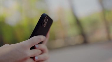 Modern bir akıllı telefonu bulanık bir açık hava ortamında tutan ve teknoloji kullanımını ön plana çıkaran bir kişinin yakın plan görüntüsü. Yakın plan Elle Tutma Akıllı Telefonu Bulanık Arkaplan ile dışarıda
