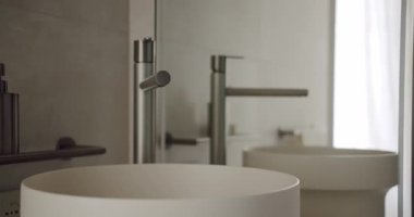 Modern bir minimalist banyo. İçinde şık bir lavabo ve musluk var. Temiz çizgiler ve yumuşak doğal ışık sakin ve çağdaş bir ortam yaratır. Modern Minimalist Banyo İçi