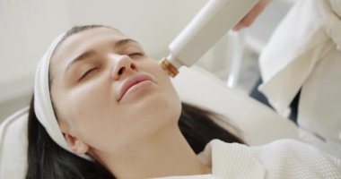 Profesyonel bir kozmetik uzmanı kadın hastalarla güzellik salonunda yüz işlemleri yapar. Yüz derisi mekanik tedavi sürecine yakın çekim. Modern teknoloji. Güzellik kraliçesiyle yüzleş.