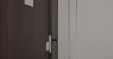 Odaya tahta bir kapıdan giren, rahat ve huzurlu bir ev ortamını gösteren bir kadının yan görüntüsü. Konforlu Ev Ortamı Odası Ahşap Kapılı Kadın Giriş Odası