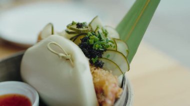 Çıtır malzemeler, taze salatalıklar, soğanlar ve siyah yumurtalarla süslenmiş güzel bir Asya yemeği sunan bao çöreğinin yakın plan görüntüsü. Japon gua bao 'suna yakın çekim,