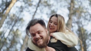 Neşeli genç bir çift, güneşli bir ormanda neşeyle gülerek, sevgi ve mutluluk göstererek sırtına biniyor. Neşeli Çift Güneşli Ormanda Sırtında Yolculuğun Tadını Çıkartıyor