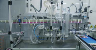 Tıp fabrikasında üretim hattı. Robot kol, ilaç paketini taşıma bandına koydu. Otomatik üretim hattında paketlenmiş mallar. İlaç imalatının üretim hattı.