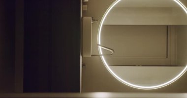 Günümüz lavabosunun üzerinde ışıklı yuvarlak bir ayna bulunan minimalist, modern bir dikey banyo. Tasarım basitliği ve işlevselliği vurgular. Modern Tuvalet İçi
