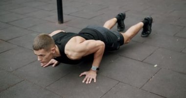 Sportif adam spor sahasında kol kaslarını çalıştırıyor ve eğitiyor. Spor ve spor yaşam tarzı. Spor, sağlık hizmetleri, sporcu kaslı güçlü vücut geliştirme. Kollarını kaldırarak şınav çekiyorlar.