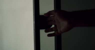 Buzlu cam kapıya hafifçe dokunan bir elin siluetini yakalayan gizemli bir görüntü entrika ve mahremiyet hissi yaratıyor. Düşük Işıkta Donmuş Cam Kapıya Dokunan Bir Elin Silüeti