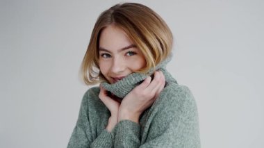 Gülümseyen ve yeşil balıkçı yaka kazağının yakasını tutan neşeli genç bir kadının portresi. Moda ve yaşam tarzı temaları için mükemmel. Gülümseyen Yeşil Süveterli Genç Kadın