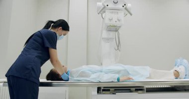 Modern laboratuardaki karın röntgeni tarama işlemi sırasında tek kullanımlık bornozlu kadının sol ve sağ görüşünü al. Hastane Radyoloji Odası. Kırıklar, kırık uzuvlar, yaralar taranıyor.