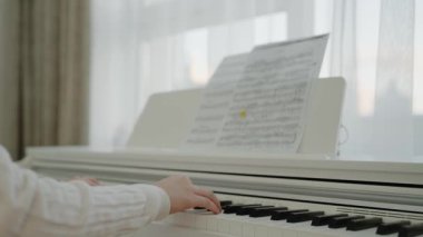 Genç kız evde piyano çalışıyor. Eğitim ve öğrenim geliştirme konsepti. Odaklanmış genç, güzel bir kız. Elektrikli piyano çalarak eğleniyor. Nota okuyorum. Piyano öğrenme dersleri