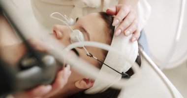 Yüz tazeleme, koruyucu gözlüklü güzel bir kadın estetik ilaçlar uygulanacak. Bir tıp merkezinde lazer yüz tedavisi gören genç bir kıza yakın çekim, cilt gençleştirme