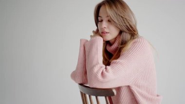 Hoş pembe balıkçı yaka kazaklı düşünceli genç bir kadının portresi yansıtıcı bir ifadeyle başka tarafa bakıyor. Basit, zarif bir arka plan. Rahat pembe kazaklı düşünceli genç kadın içeride poz veriyor.