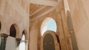 Güneş ışığı Casablanca, Fas 'taki Hasan II Camii' ne akarak karmaşık fayans çalışmalarını ve süslü kemerleri aydınlatıyor. Kamera büyük iç mekânda yankılanıyor.,