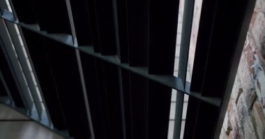 Çağdaş dış tasarım ve mimari detaylar sunan yıpranmış tuğla bir duvarın bitişiğindeki ahşap bir güvertedeki siyah metalin yakın çekim görüntüsü..