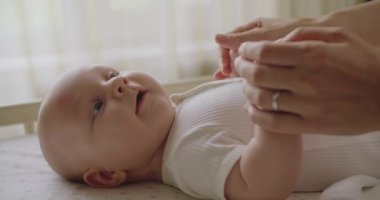 Annenin bebek bebekle nazikçe konuştuğu, küçük ellerini tuttuğu ve çocuk odasında öpüştüğü yakın plan. Annesiyle gülümseyen sevimli, neşeli bir bebek. Ebeveynlik kavramı. Annelik kavramı.