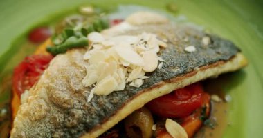 Patates püresi ve sebzeli güzel dekore edilmiş beyaz balık parçası yeşil tabakta ve beyaz arka planda dönüyor. Soslu levrek. Restoran ana yemek konsepti. Kapat..