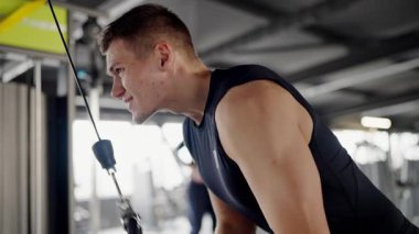 Odaklanmış genç bir adam, iyi donanımlı bir spor salonunda güçlü ve dayanıklı halatlar kullanarak yoğun bir şekilde antrenman yapar. Genç Adam Spor Salonunda Savaş Halatlarıyla Egzersiz Yapıyor Odaklanıyor ve Kararlı.