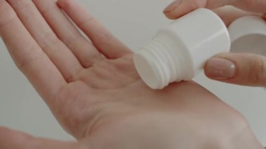 Küçük bir konteynırdan beyaz haplar döken, ilaç, sağlık ve tedaviyi temsil eden bir elin yakın çekimi. Tıbbi, ilaç ve sağlık kavramları için idealdir. El Bir Hap Alırken