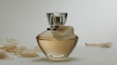 Gül yapraklı sofistike parfüm şişesi lüks ve zarafet hissi yaratıyor. Güzellik, parfüm ve lüks yaşam tarzı temaları için ideal. Gül yapraklı zarif parfüm şişesi.