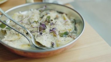 Mikro yeşilliklerle süslenmiş ve kremalı sosla servis edilen lezzetli bir ravioli yemeği. Zarif yemekler ve güzel yemekler sergilemek için mükemmel. Taze Herb Garnitürlü Kremalı Ravioli