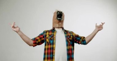 At maskesi takan bir adam beyaz arka planda dans eder. Bu komik videoda kimsenin izlemediği gibi dans ederken eğleniyor ve kutluyor..