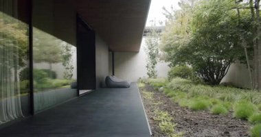 Çağdaş bir evin dış yüzeyini keşfedin. Yeşillik bir bahçe ve konforlu dinlenme alanı, doğa ile mükemmel bir uyum içinde. Yazın modern evin önünde teras..