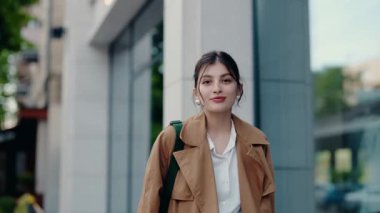 Şık bir palto giyen genç bir kadın, şehir ortamında dışarıda dikilirken kendine güvenerek gülümsüyor. Modern şehir hayatını, zarafeti ve olumlu titreşimleri yansıtıyor. Zarif Giyinimli Kadın Dışarıda