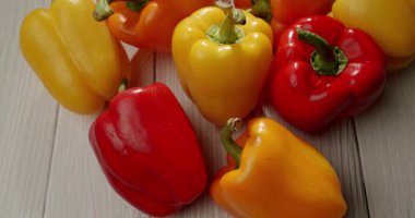 Açık ahşap bir yüzeye sarı, kırmızı ve turuncu dolma biberlerden oluşan canlı bir çeşitlilik. Taze, sağlıklı sebzelerin, organik ürünlerin ve mutfak malzemelerinin mükemmel bir temsili..