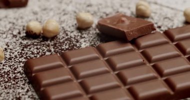 Kakao tozunun üstünde fındıklı sütlü çikolatanın yakın çekimi. Tatlıları, tatlıları ya da çikolata ürünlerini teşvik etmek için mükemmel. Lezzetli Sütlü Çikolata