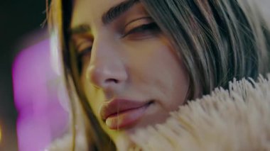 Bokeh beyaz arka planda genç ve güzel bir kadının portresi. Yakın çekim. Şehrin beyaz ışıklarıyla caddede dikilirken kameraya bakan güzel bir kadın model. Şatafatlı kadın Alacakaranlık Sokağı kamerasına bakıyor..