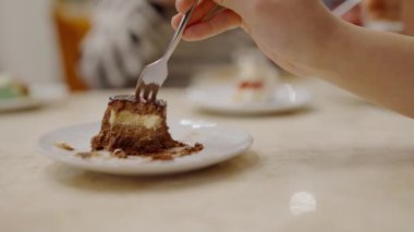 Kapalı Kapılar Arasında Lezzetli Tatlılar 'ın tadını çıkarıyorum. Beyaz bir tabakta kısmen yenmiş bir tatlıyı yakından görmek. Bulanık bireylerin arka planda yemeğin keyfini çıkarması..